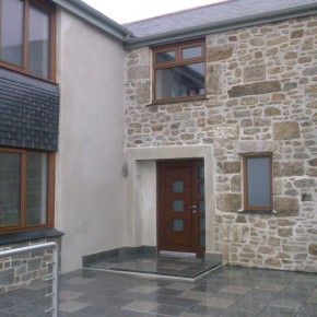 Door alcove in lime . Door surround in lime over an unattractive cast concrete lintel . The wall is rendered block with lime pointing and wet laid vertical slate.