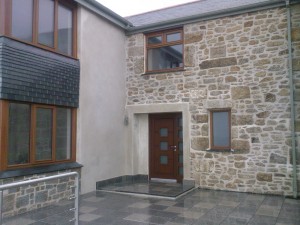 Door alcove in lime . Door surround in lime over an unattractive cast concrete lintel . The wall is rendered block with lime pointing and wet laid vertical slate.